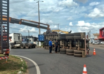 Carreta carregada de sucata tomba em rotatória de Várzea Grande; veja vídeos