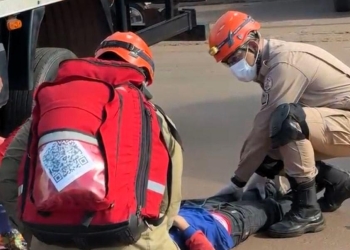 Motociclista colide com caminhão durante manobra e fica preso sob o veículo